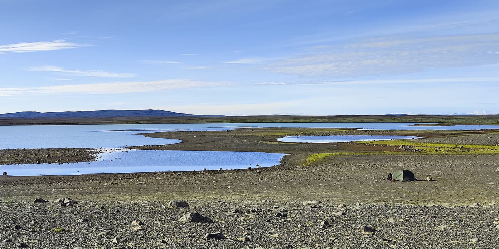 pitched tent near body of water in Iceland on the iceland crossing