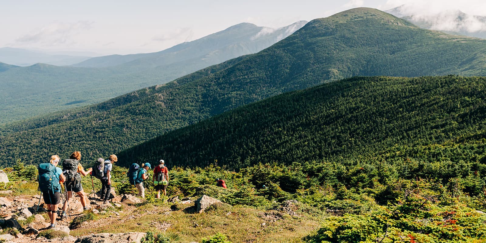 group of hikers hiking towards green mountains on the Appalachian hut to hut tour