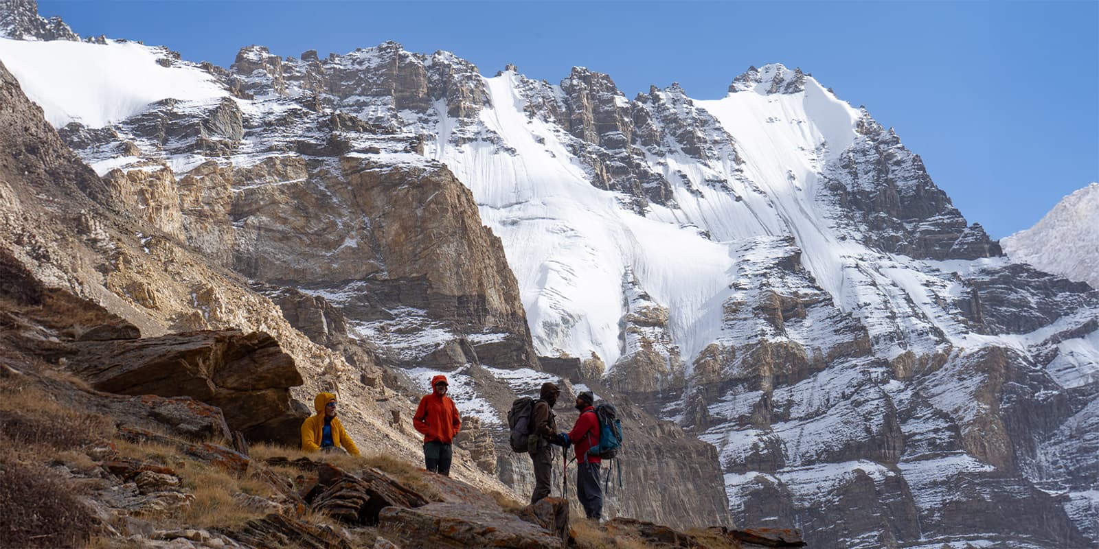 group of hikers standing in front of huge mountain peak on the Pamir Trail