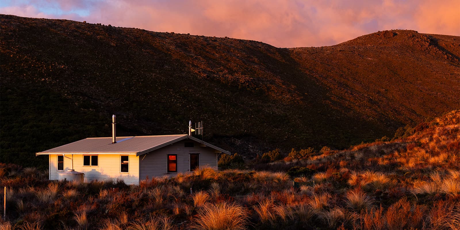 small white house in grassy landscape during sunset