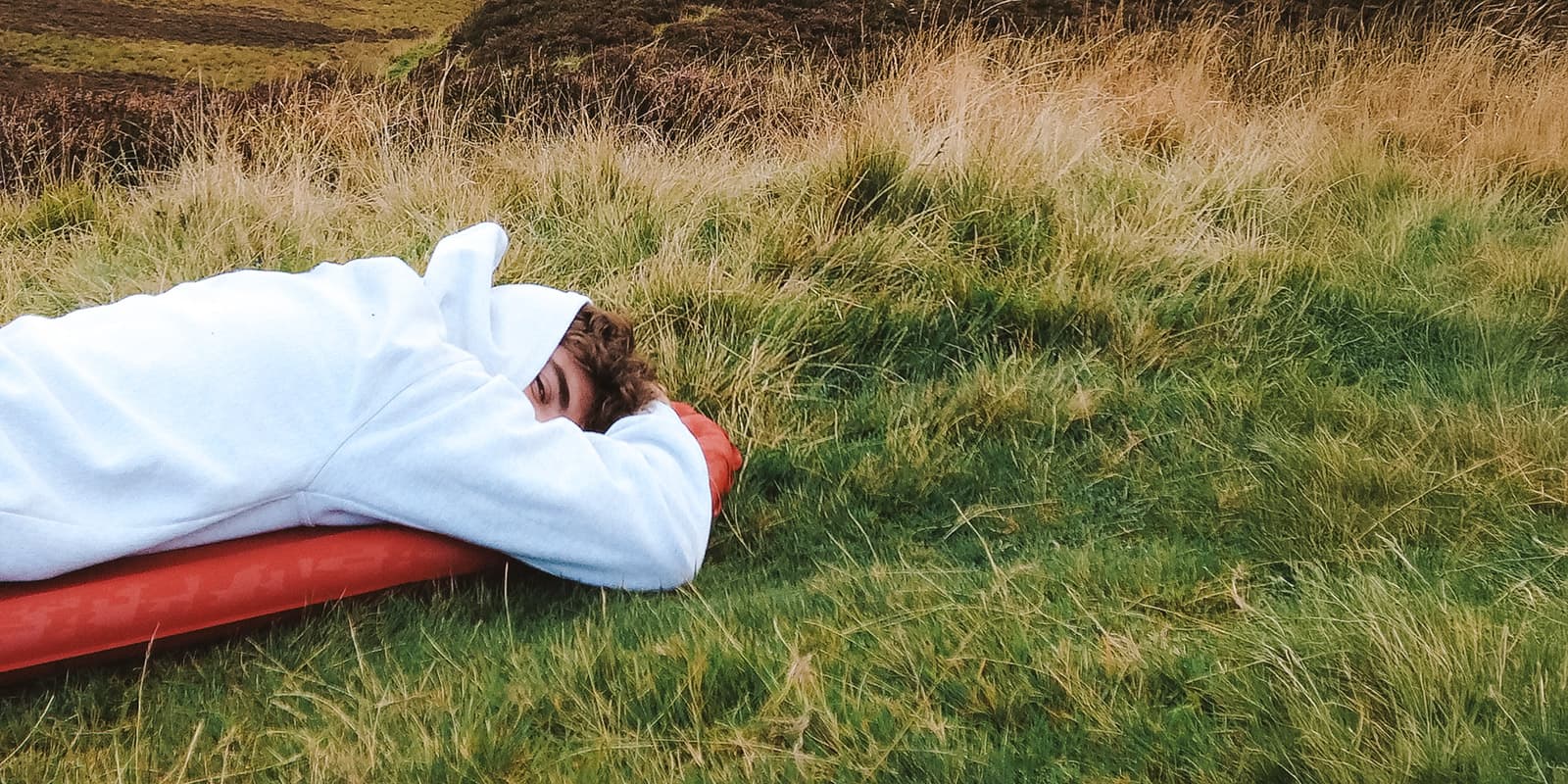 man lying down on sleeping mat in grass