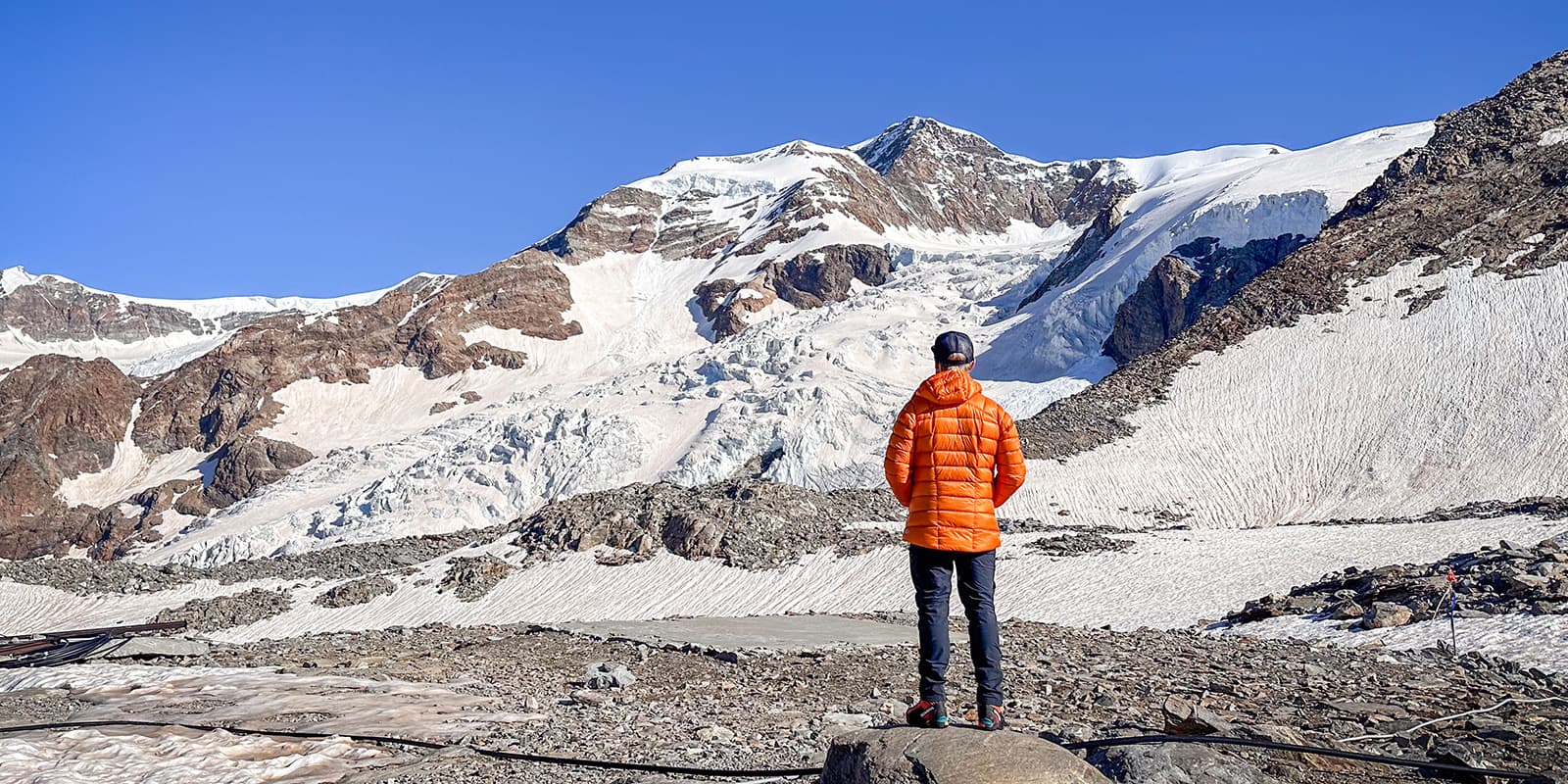 person standing in front of icy mountains wearing the RAB mythic alpine down jacket