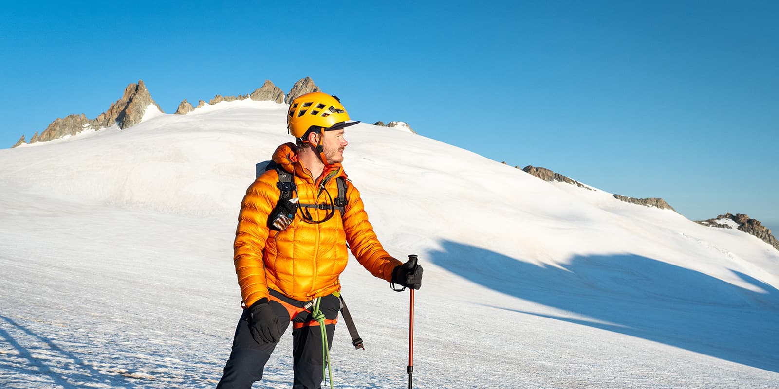 person climbing snow capped mountains wearing the RAB mythic alpine down jacket