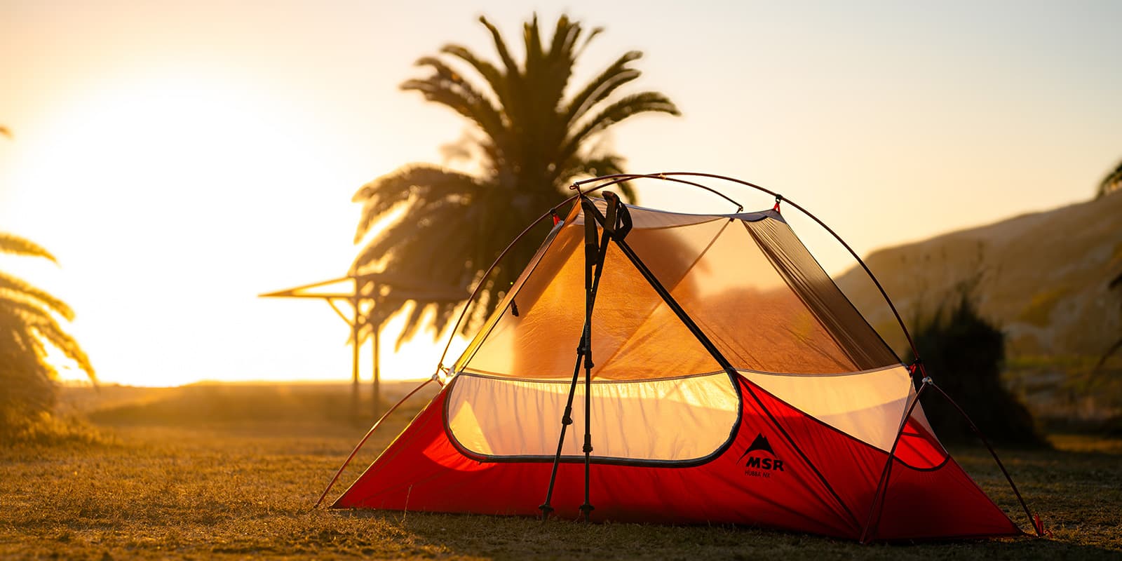 hiking poles resting on MSR tent near the beach at sunset