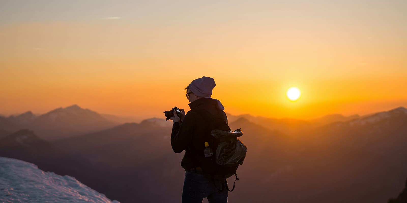 person with camera in the mountains at sunset