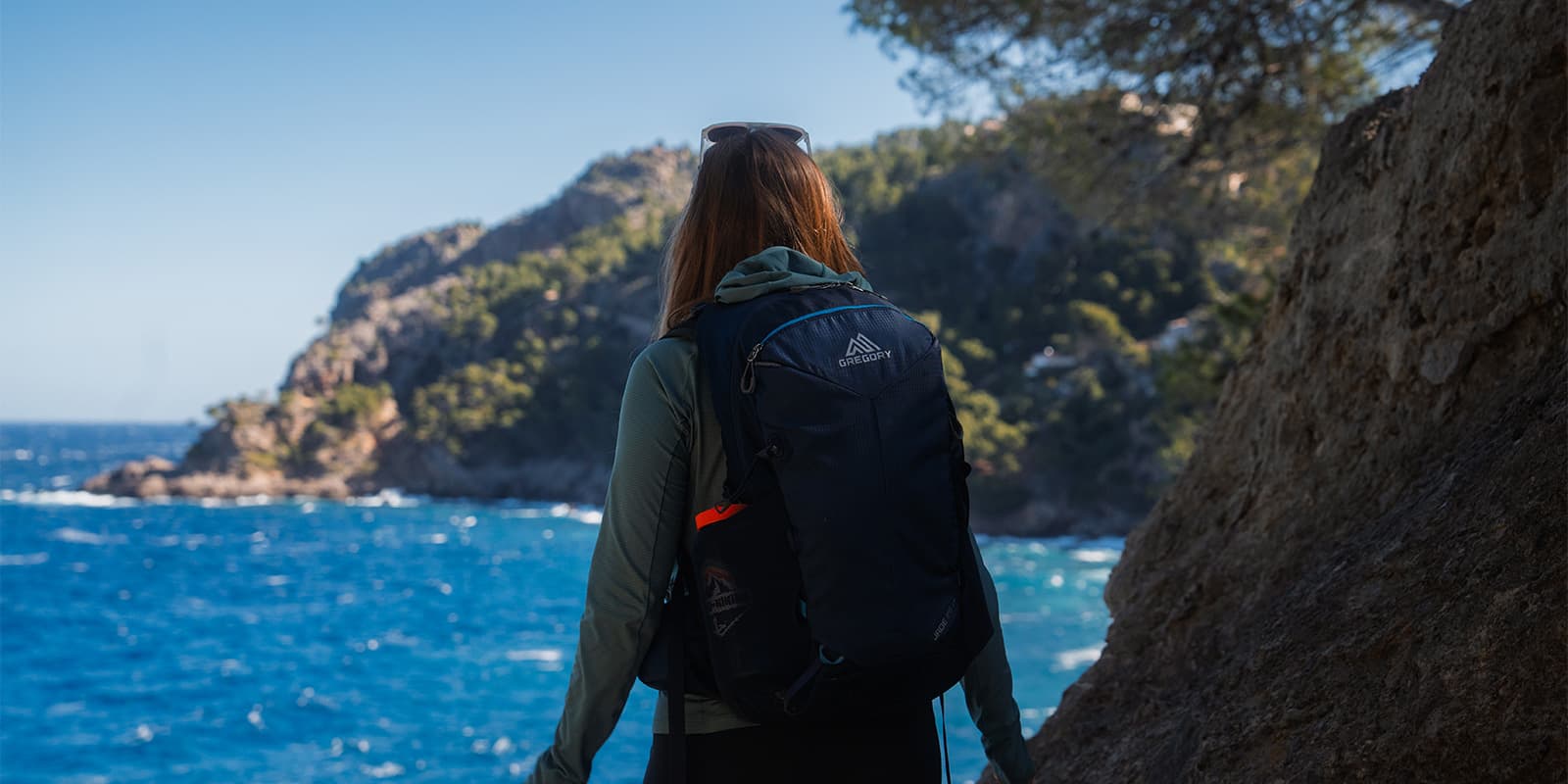 person overlooking the ocean on Mallorca wearing a blue Gregory backpack