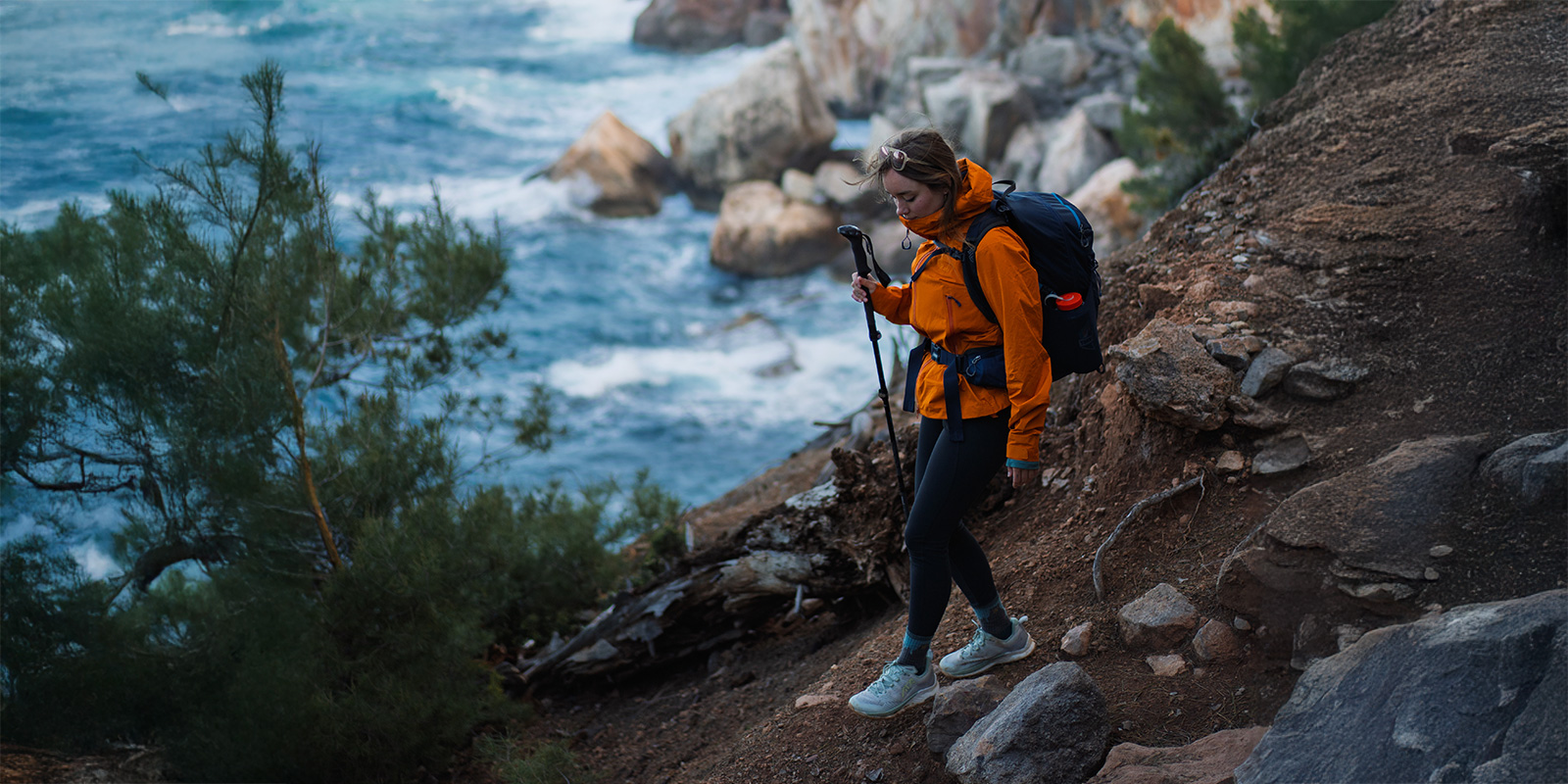 person hiking down trail next to ocean on Mallorca