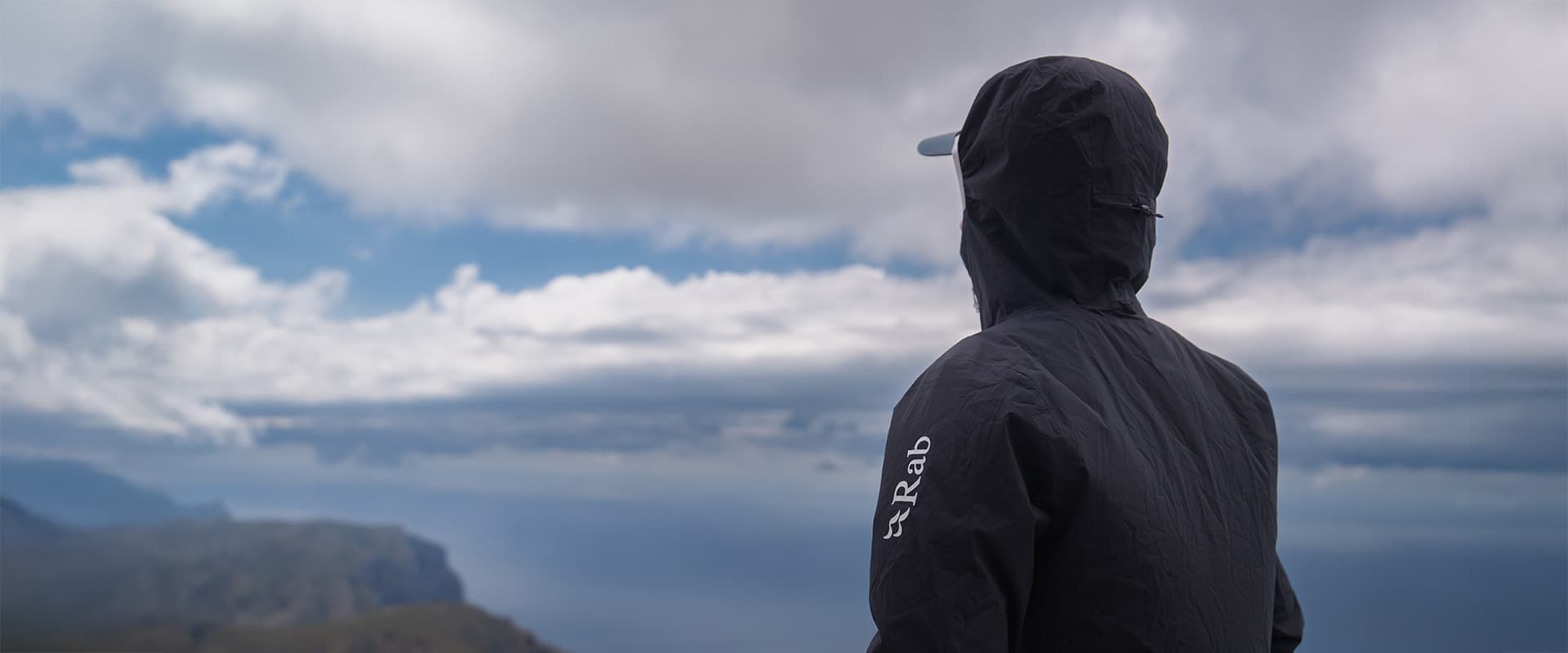 person overlooking the mountains of Mallorca wearing a RAB jacket