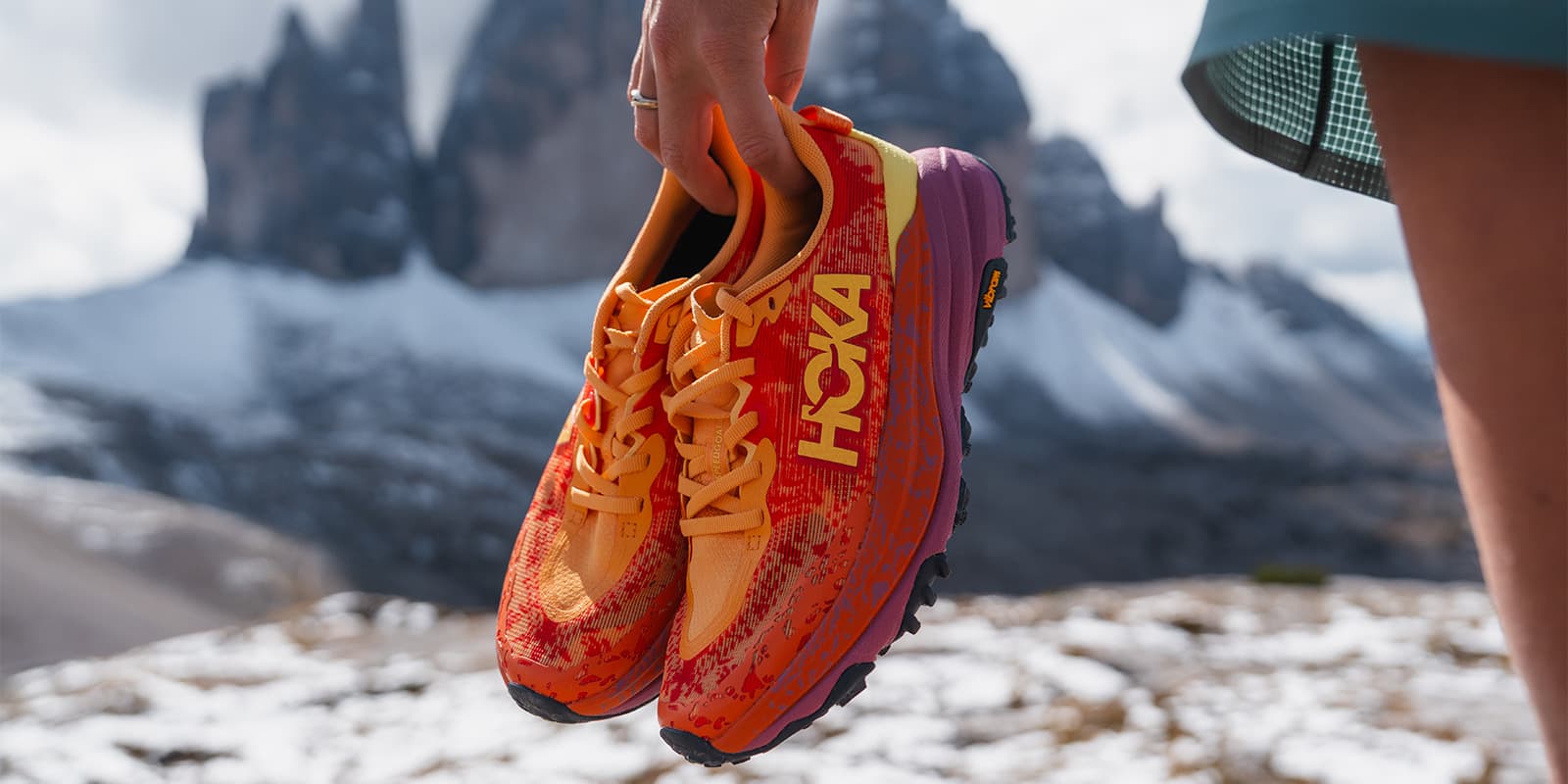 person holding her trail running shoes by Hoka