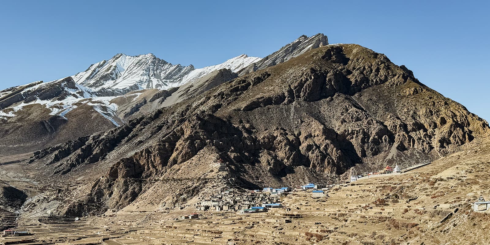 old town in the middle of the mountains of Nepal with big mountains in the background