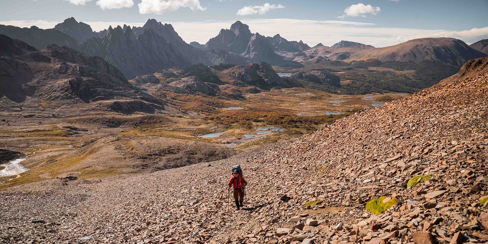 hiker on gravel mountain trail with mountains in the background in the south of Chile