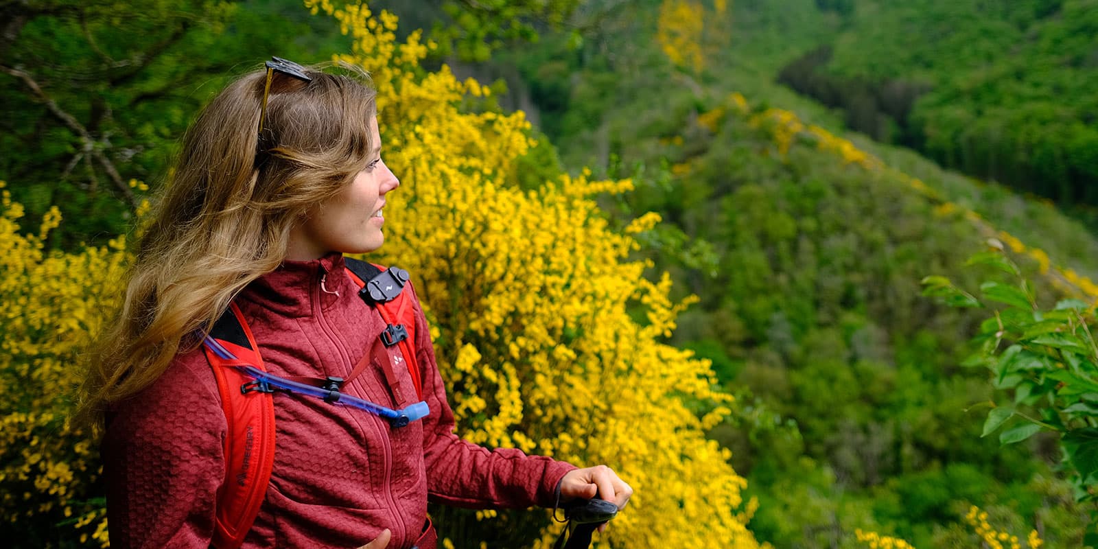 person looking at green landscape in Luxembourg wearing red Vaude fleece jacket