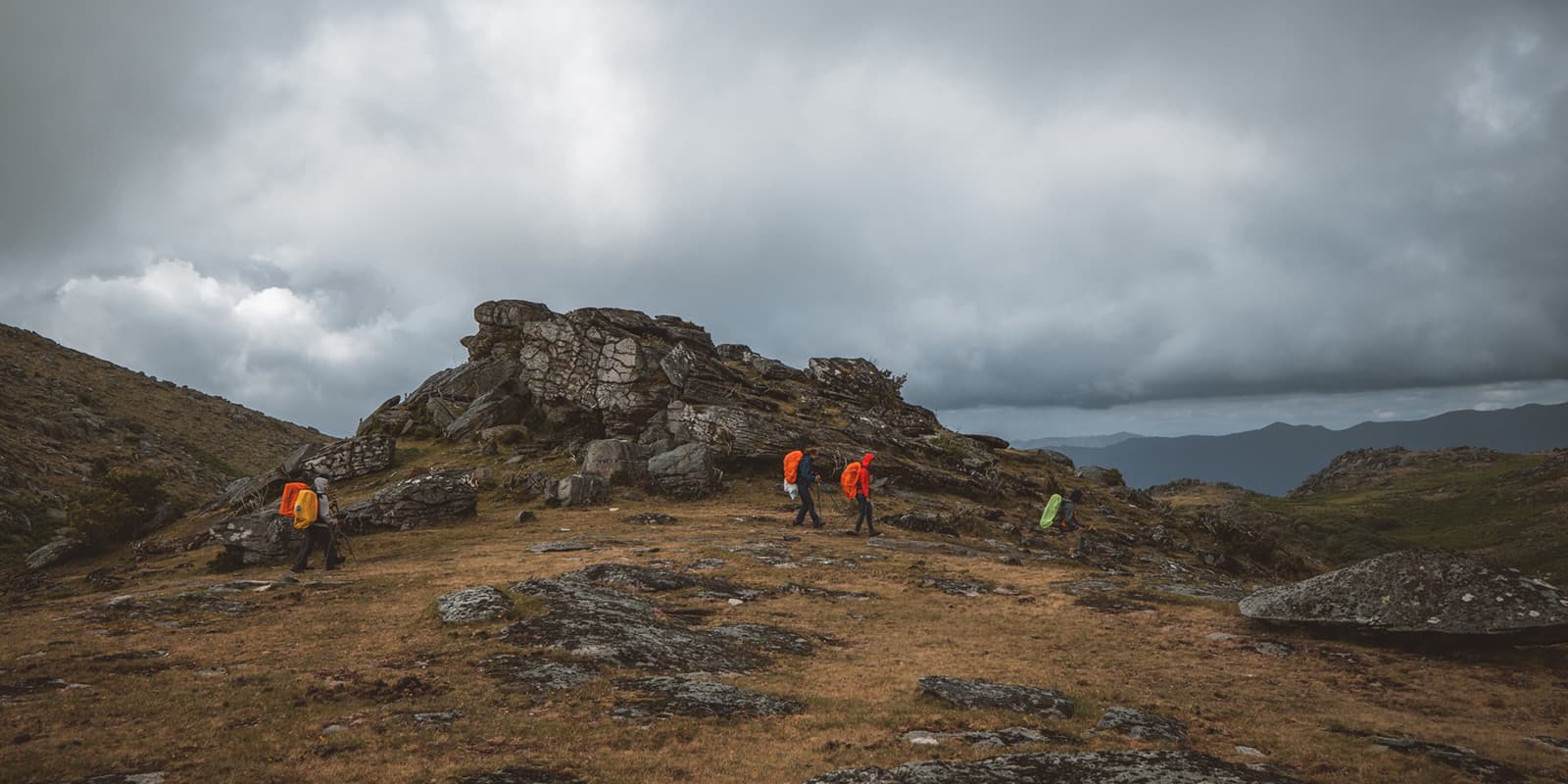 group of hikers in the mountains with dark clouds above them
