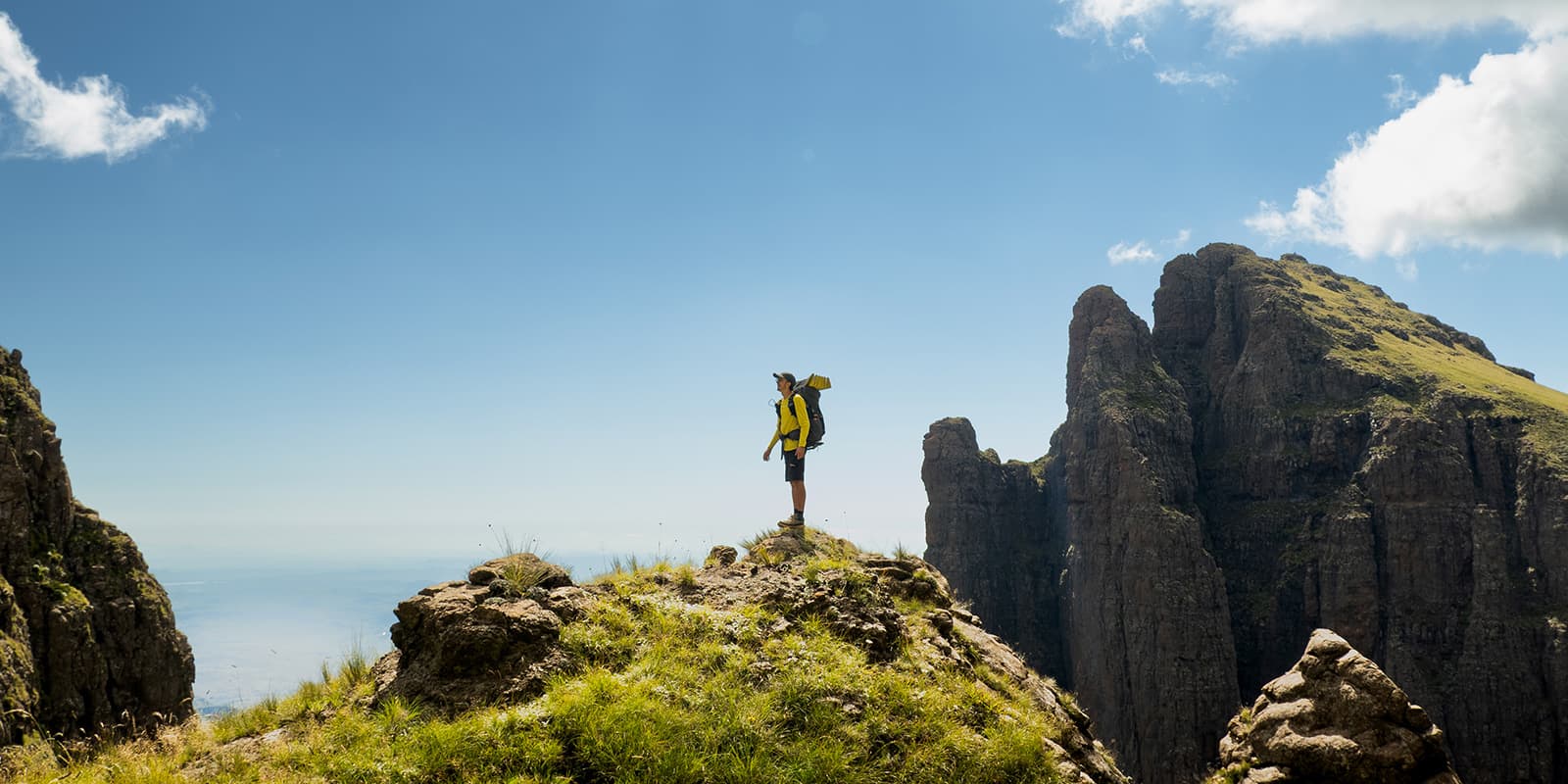 person standing on a rock against the blue sky with mountains in the background