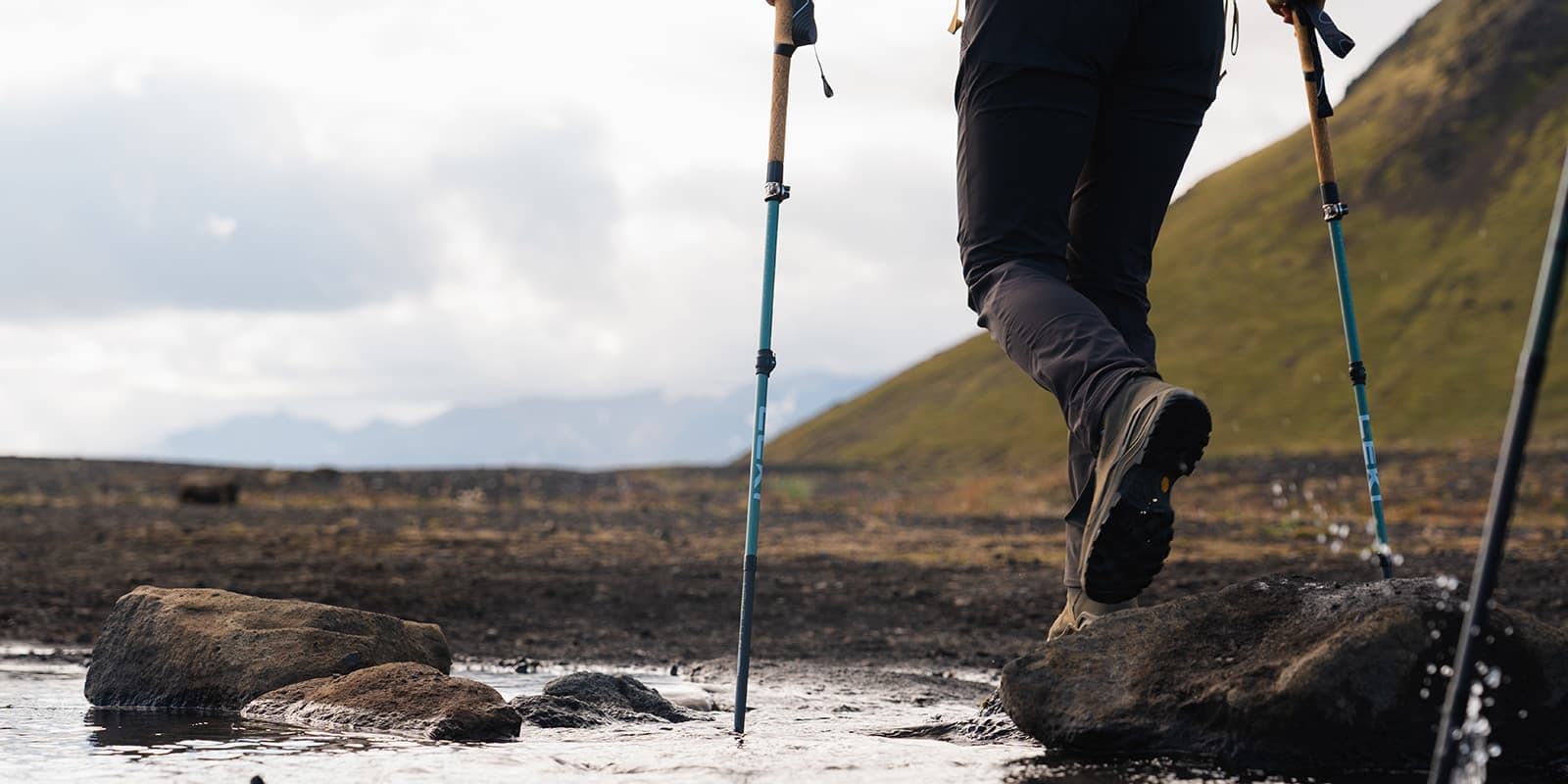 person crossing small river using her Leki Makalu poles to balance