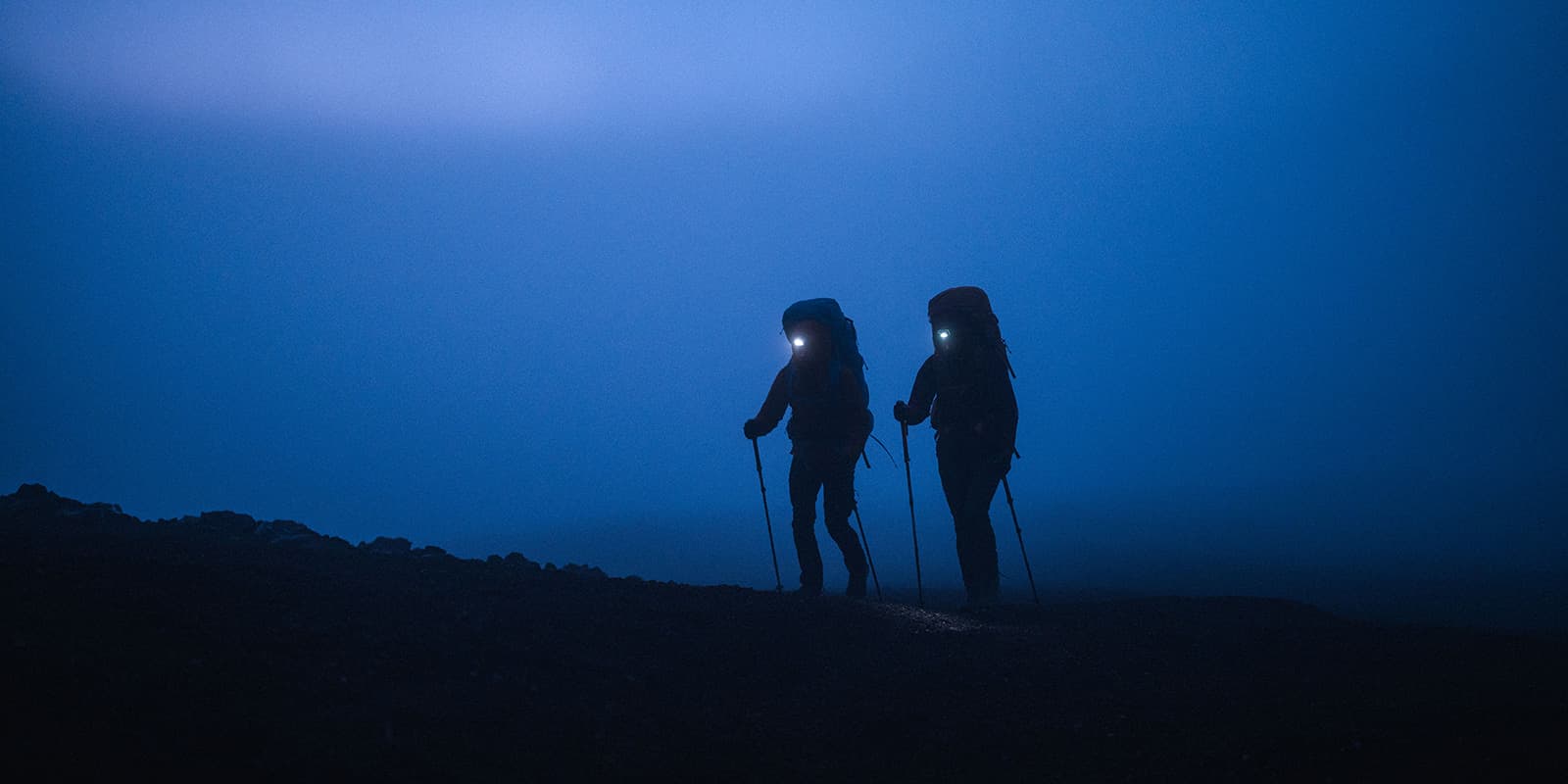 couple hiking during blue hour with headlamps on