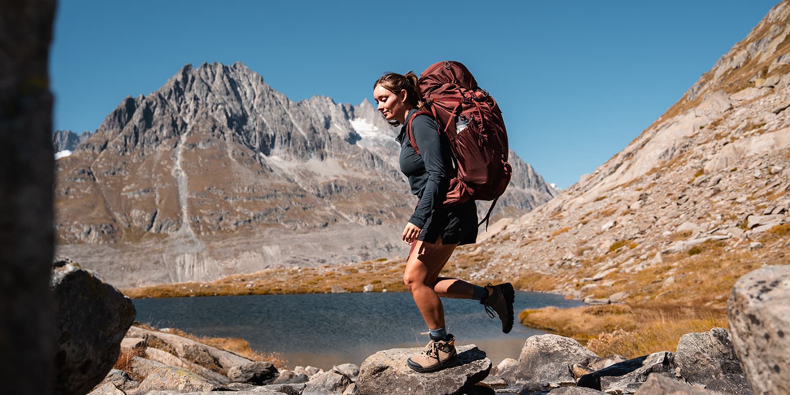 women hiking over stones with mountains in background