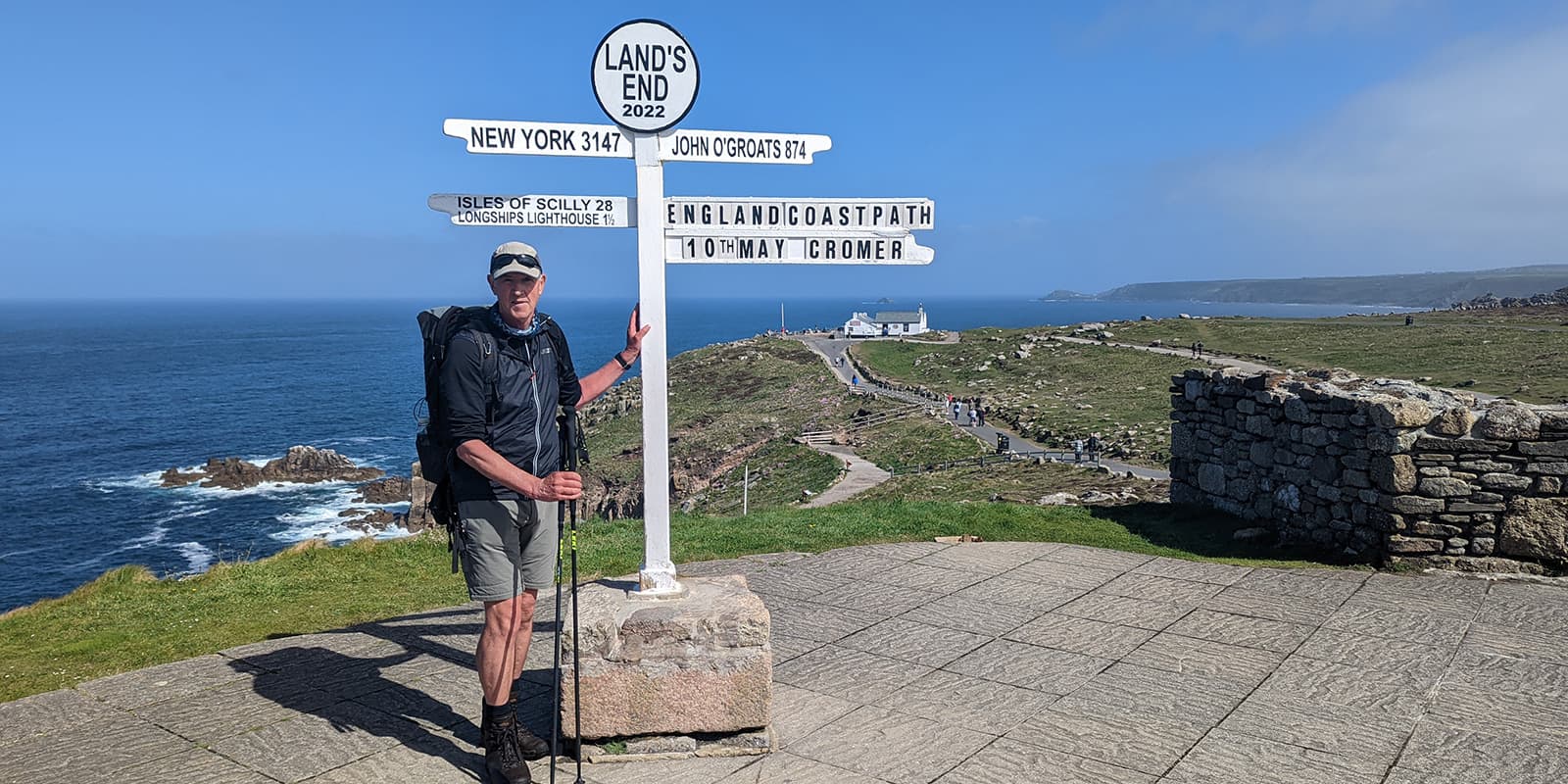 person standing next to trail marker on the England Coast path