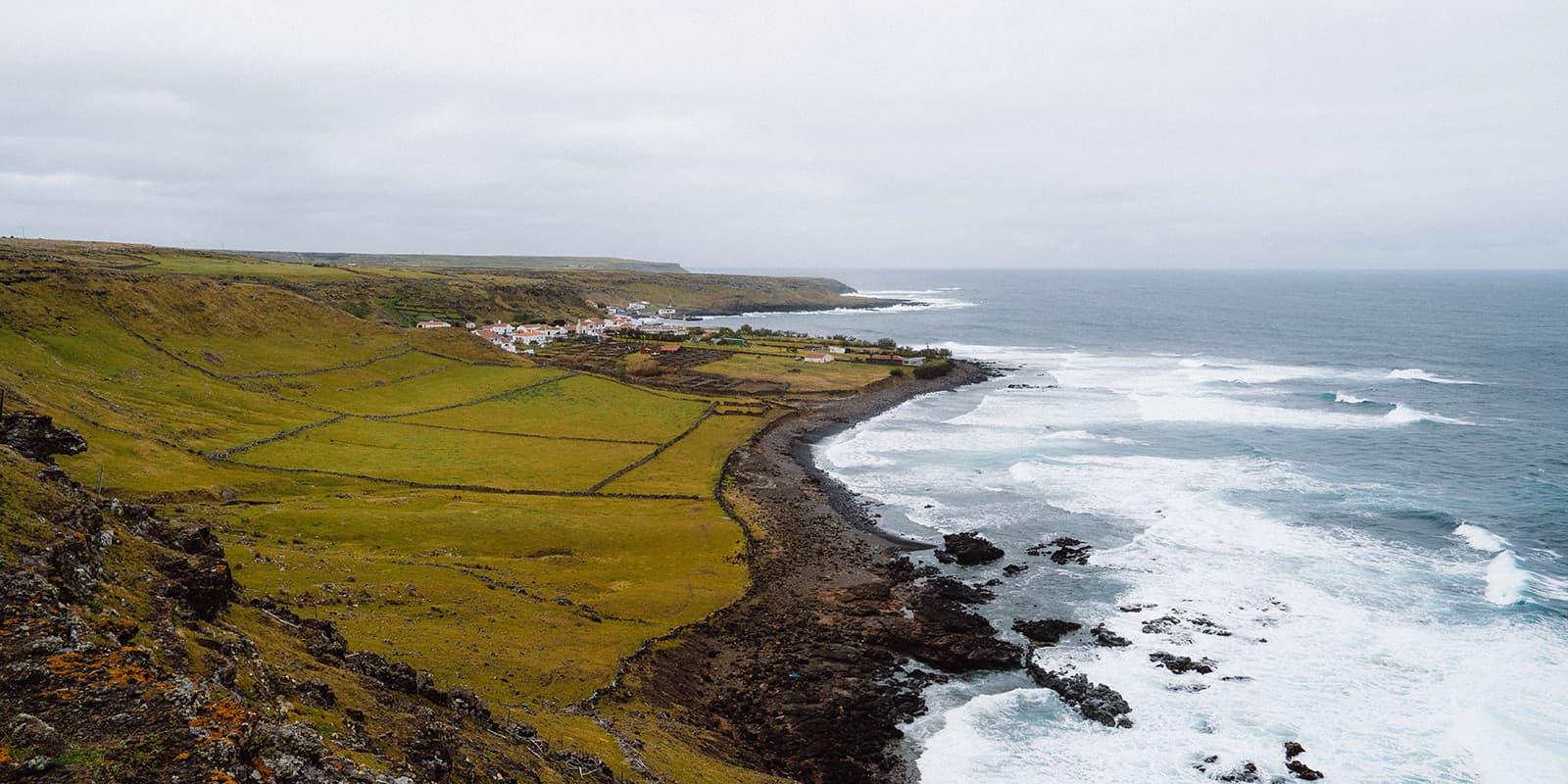 couple hiking towards the ocean with cliffs of Santa Maria Azores in the background