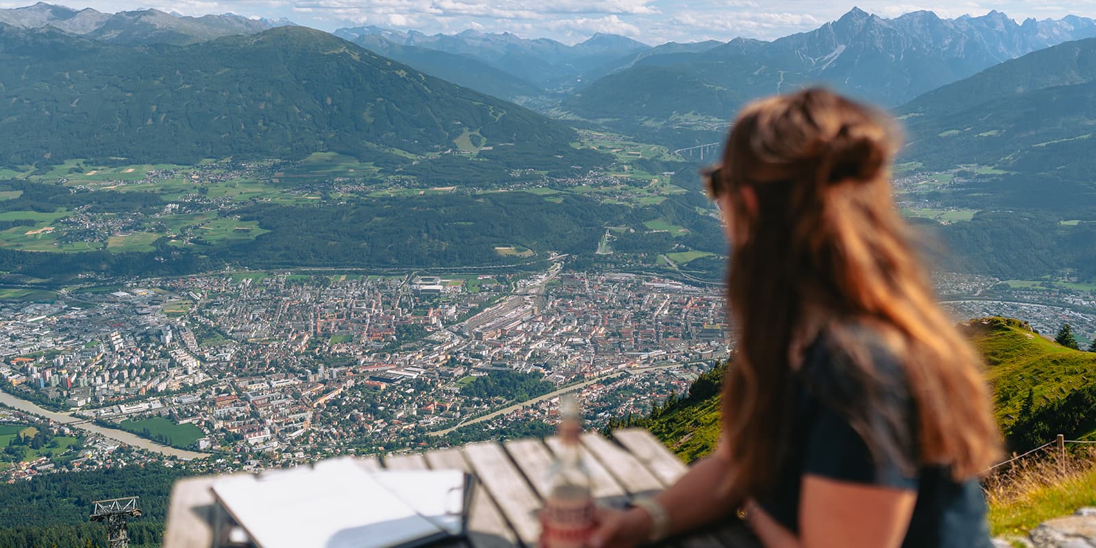 person having a drink and looking down at the city of Innsbruck