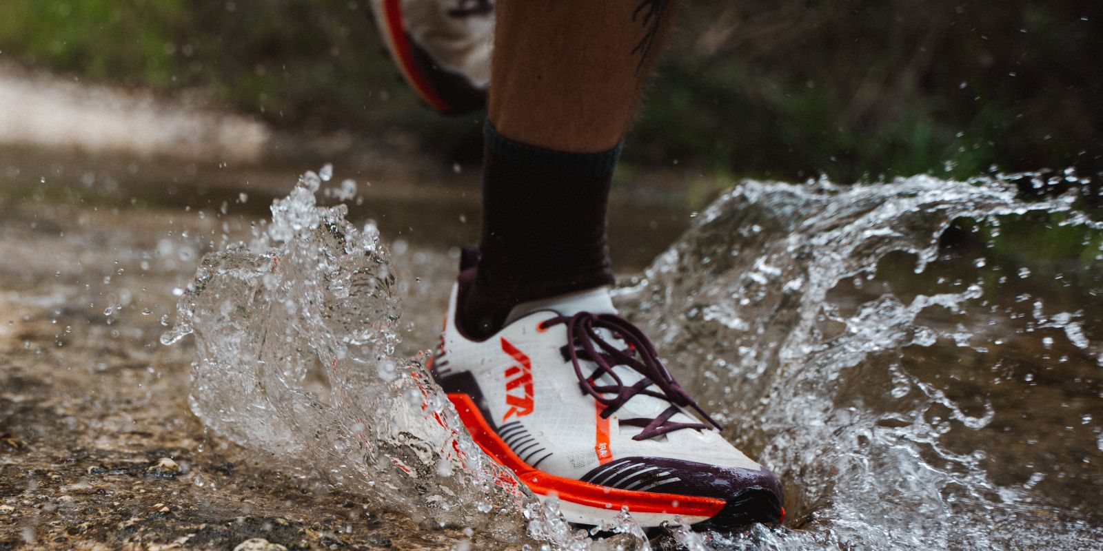 Someone running through a puddle, creating a splash, while wearing the LOWA SKYTERRA shoes