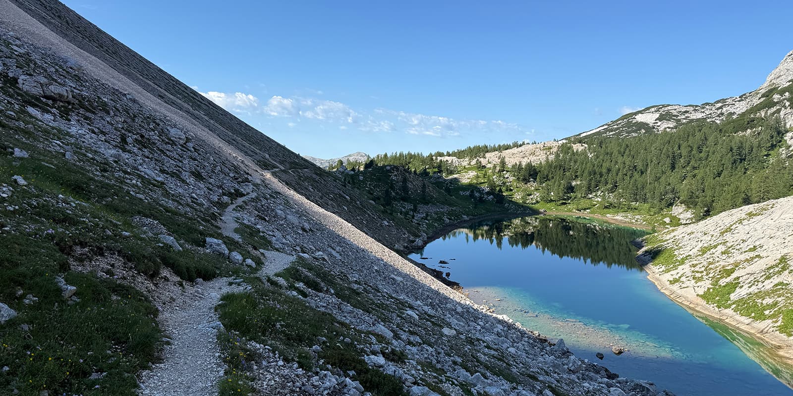 narrow hiking trail on the side of a mountain near body of water