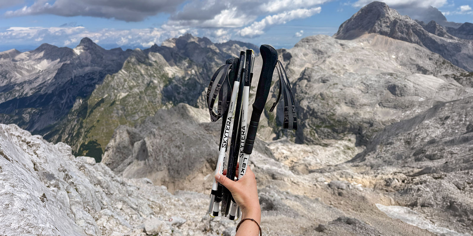 person holding hiking poles with mountains in background